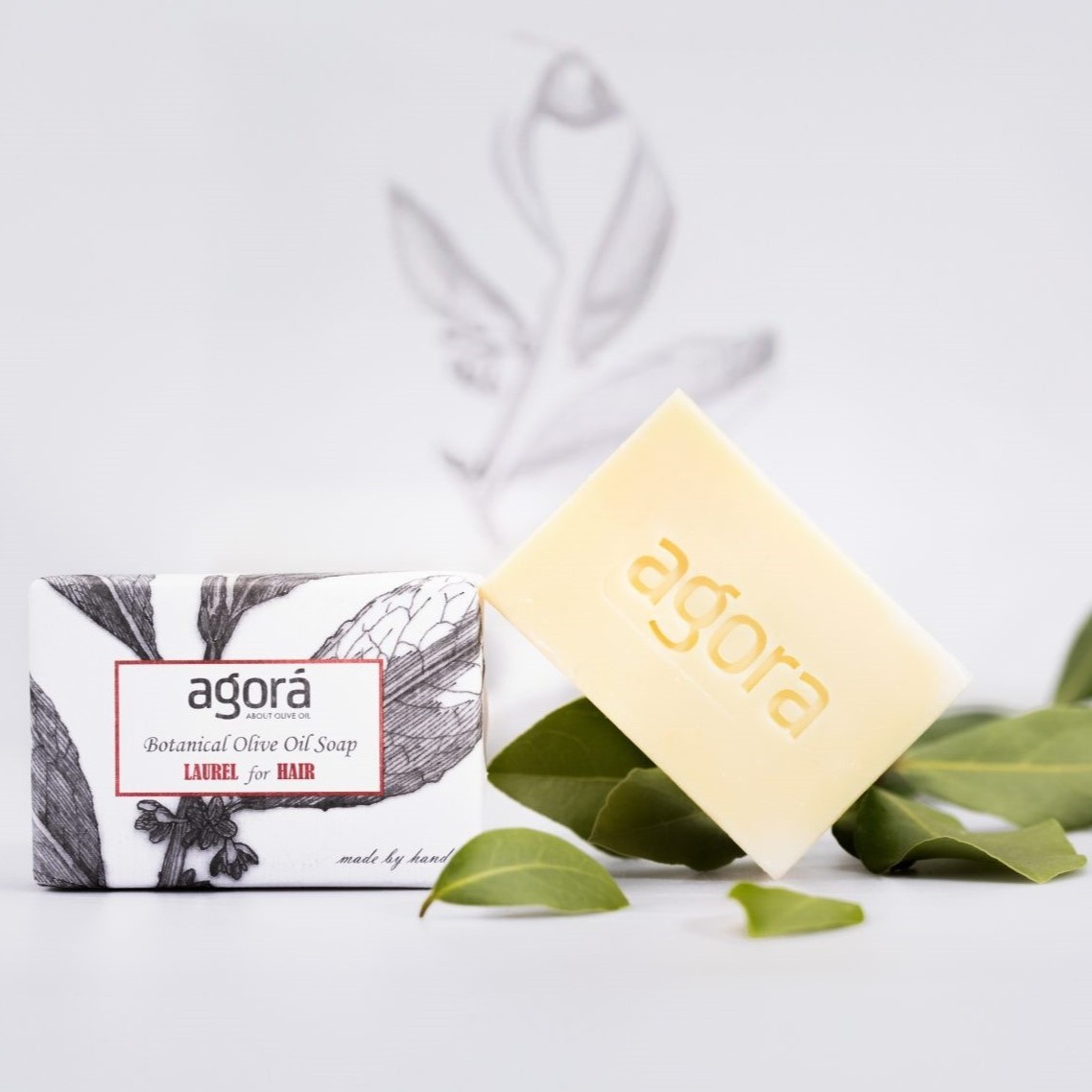 Handmade laurel olive oil soap for hair and scalp by Agorá, pictured with fresh bay leaves and minimalist packaging